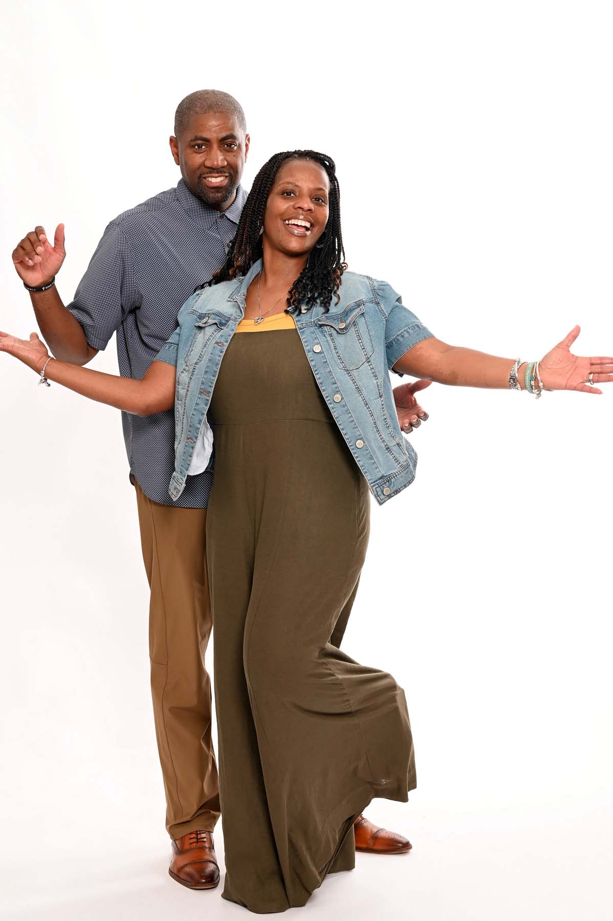 Pastor Larry and First Lady Tamecia Smith stand side by side with open arms and warm smiles, conveying a welcoming and joyful atmosphere in a bright church setting with soft lighting and inviting decor